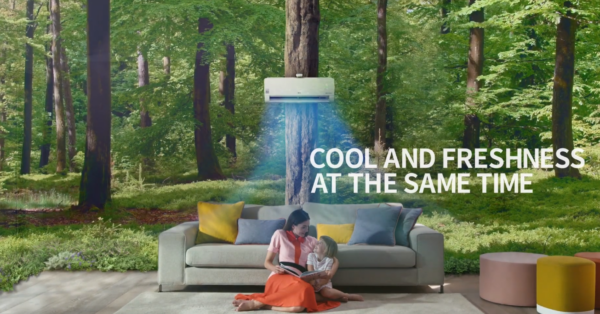 A picture of woman and child reading a book as they sit under LG DUAL COOL, as if they’re sitting in the middle of a dense forest