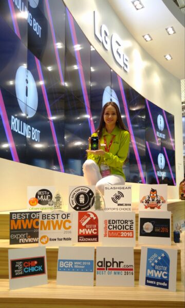 An LG promotor at MWC 2016 holds the LG G5 in her hand while standing behind 15 Best of MWC awards for the LG G5